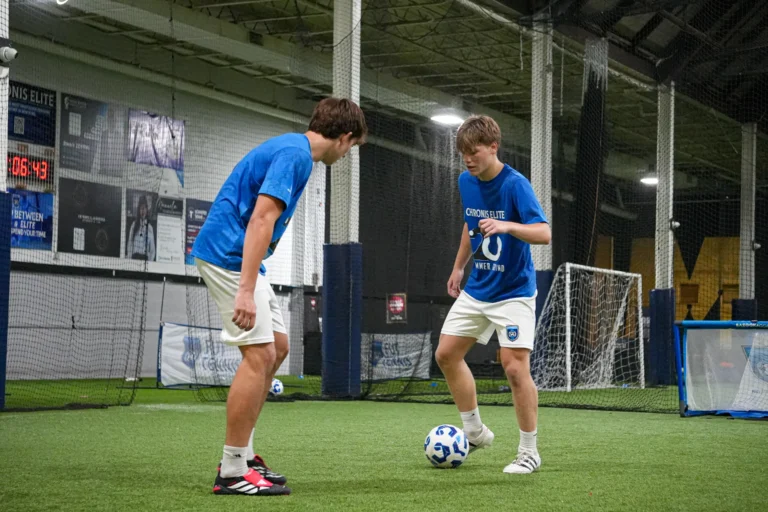 Two teenage soccer players practicing one-on-one ball control during an indoor Summer Grind session